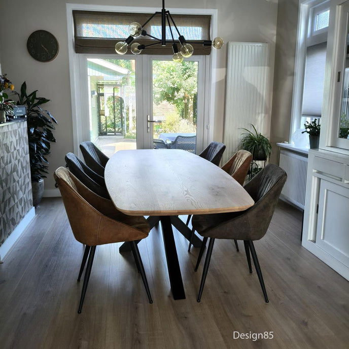 Moderne Eettafel Deens Ovaal Fjord van Design85 met ovaal eikenhouten tafelblad en zwart stalen frame in een sfeervolle eetkamer.