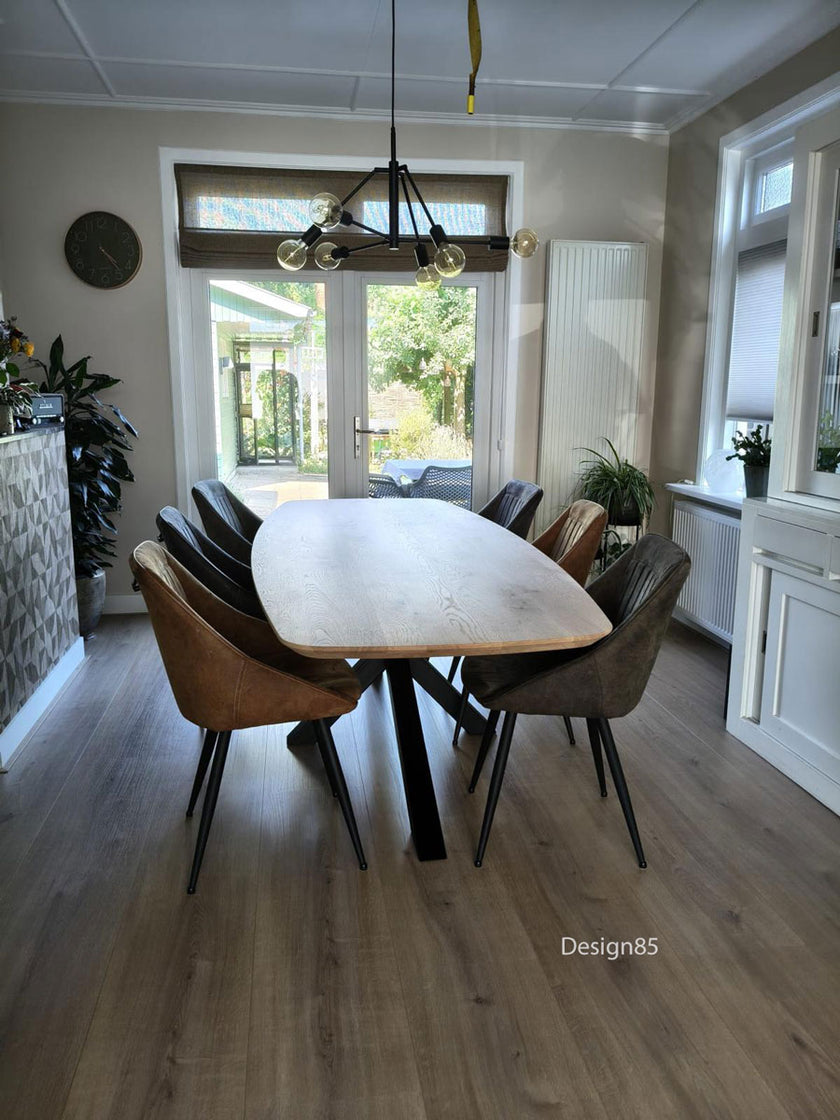 Moderne Eettafel Deens Ovaal Fjord van Design85 met ovaal eikenhouten tafelblad en zwart stalen frame in een sfeervolle eetkamer.