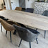 Eettafel Deens Ovaal Fjord met natuurlijke houtnerf en industrieel onderstel, omringd door comfortabele antracietkleurige eetkamerstoelen.