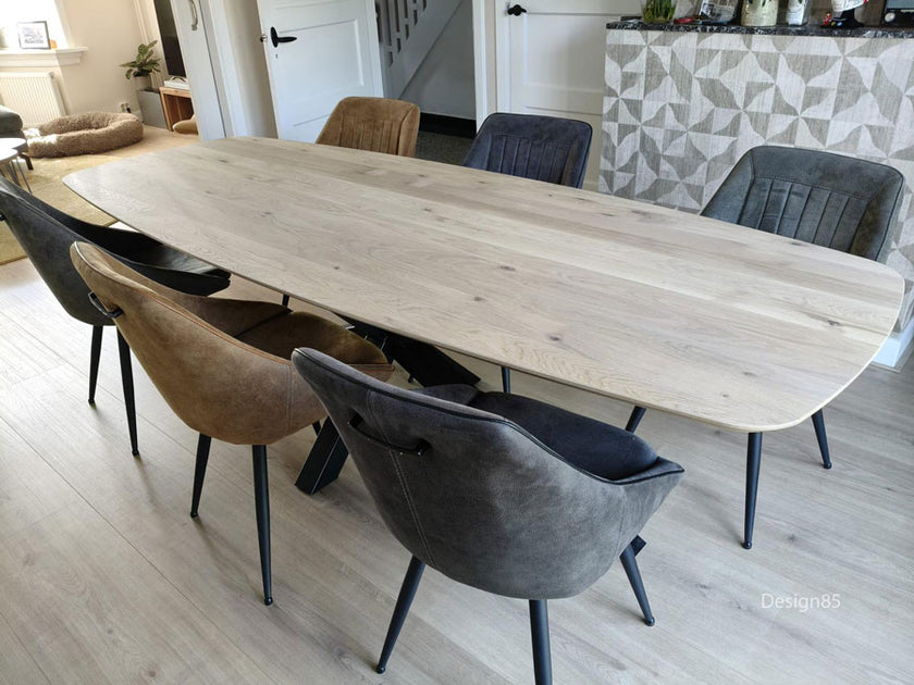 Eettafel Deens Ovaal Fjord met natuurlijke houtnerf en industrieel onderstel, omringd door comfortabele antracietkleurige eetkamerstoelen.