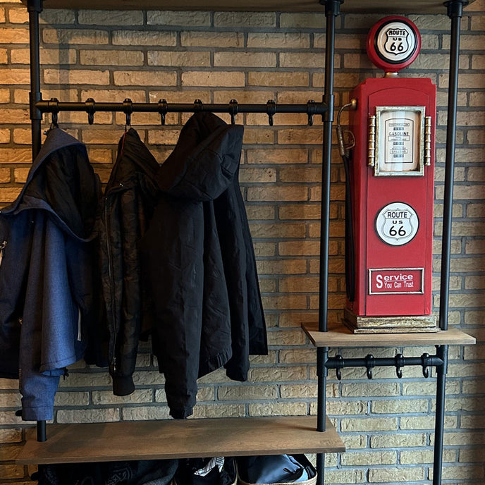 industriele kapstok stralend met een stenen muur en hoeden op de bovenste legplank.