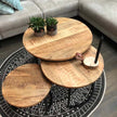 ronde salontafel mango met 2 plantjes en een kaars op een zwart kleed met een bank op de achtergrond 