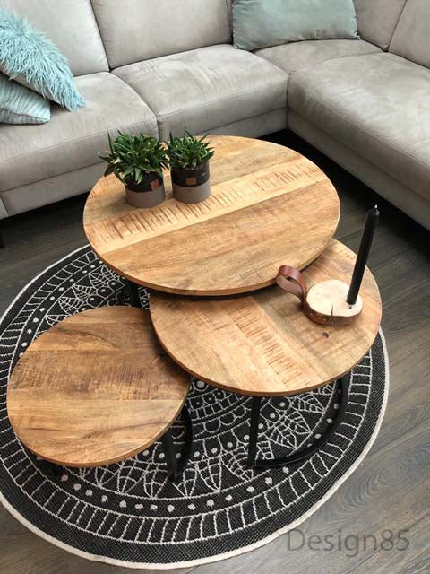 ronde salontafel mango met 2 plantjes en een kaars op een zwart kleed met een bank op de achtergrond 