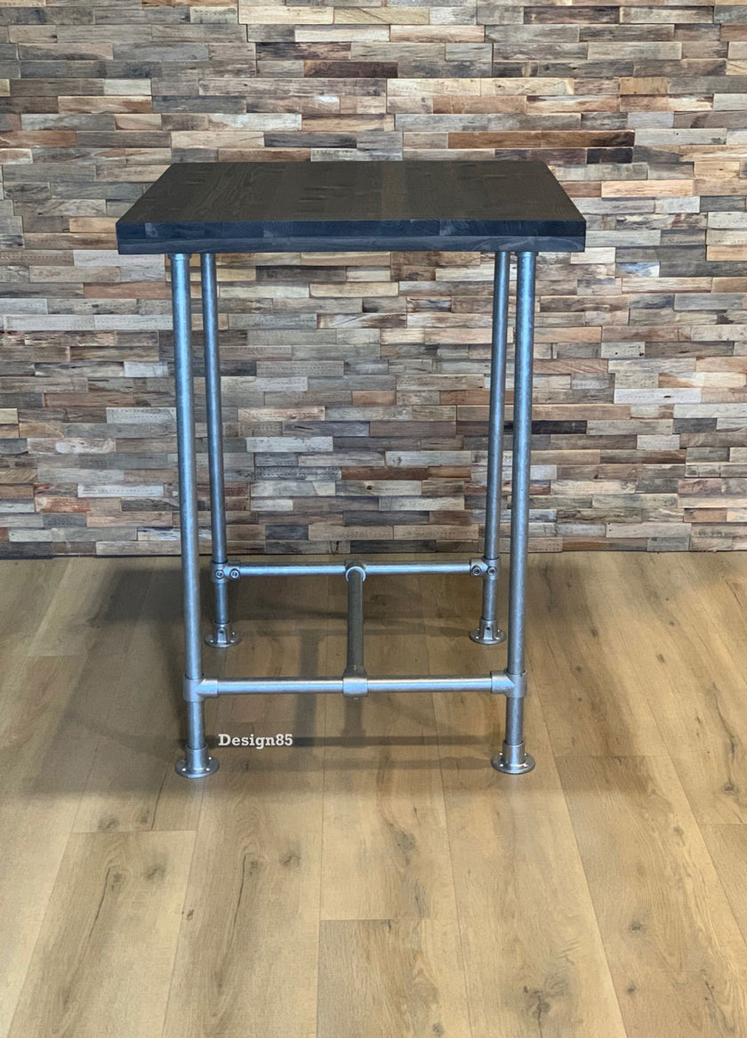 Industriële statafel met stalen buizen en houten blad tegen wand met houtlook tegels