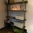 Open industriële vakkenkast met zwarte legplanken, decoratie en planten in modern interieur