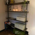 Open industriële vakkenkast met zwarte legplanken, decoratie en planten in modern interieur