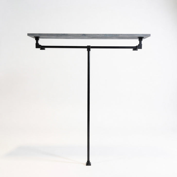 Industriële open kledingkast van zwart staal met legplank in zwarte wax op een witte achtergrond.