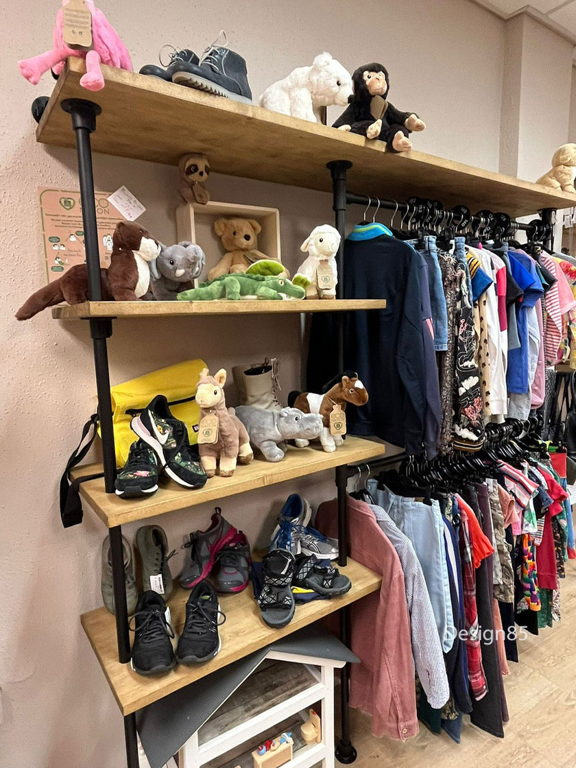 Industrieel kledingrek muur met legplanken en hanggedeelte gevuld met kinderkleding