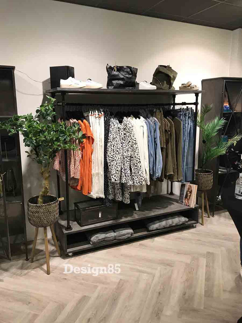 Industrieel kledingrek wielen Garderobe in een kledingwinkel, gevuld met dameskleding en voorzien van ruimte voor schoenen en tassen.