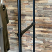 Industrieel kledingrek op wielen met twee niveaus voor het presenteren van shirts en accessoires.