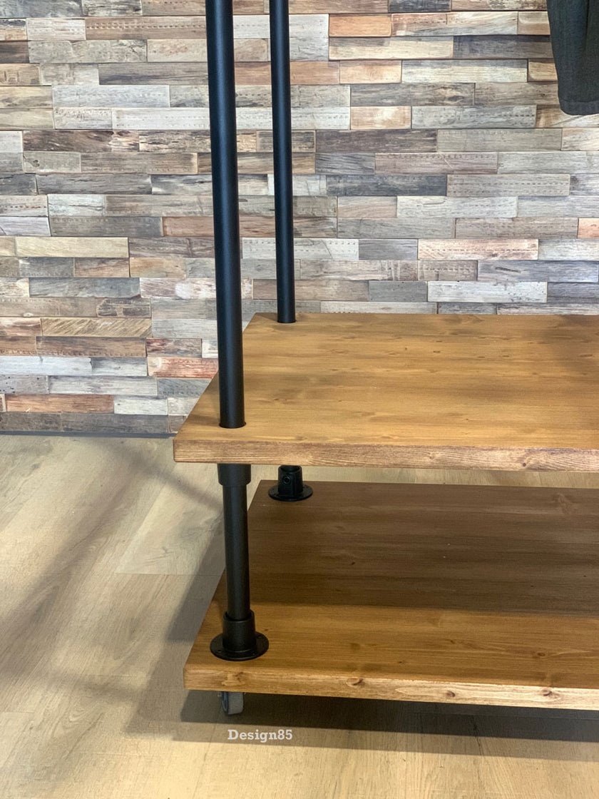 Kledingrek wielen presentatie met houten onderplanken, zwarte buizen en vier zwenkwielen.