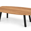 Salontafel ovaal Vince met naturel eikenhouten blad, afgeronde hoeken en vier schuine zwarte metalen poten.