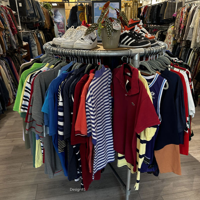 Rond steigerbuis kledingrek met kleding en sneakers in een moderne vintage kledingwinkel.