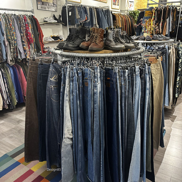 Industrieel rond kledingrek van steigerbuizen gevuld met kleurrijke polo’s en shirts in een kledingzaak.