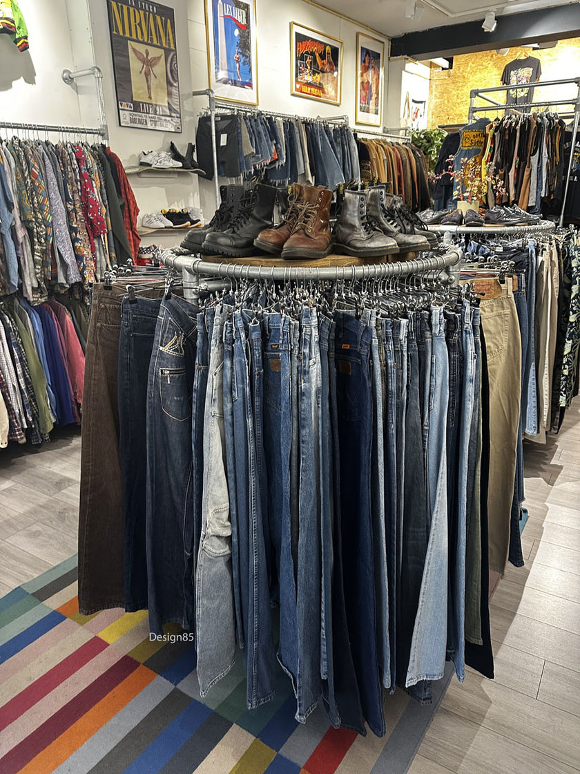 Industrieel rond kledingrek van steigerbuizen gevuld met kleurrijke polo’s en shirts in een kledingzaak.