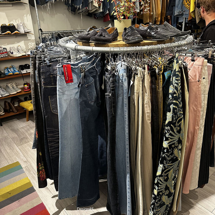 Steigerbuis kledingrek rond model met houten bovenblad en kleding rondom opgesteld in een winkelinterieur.