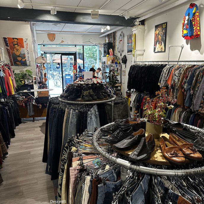 Rond industrieel kledingrek van steigerbuizen met shirts, sneakers en decoratie in een modewinkel.