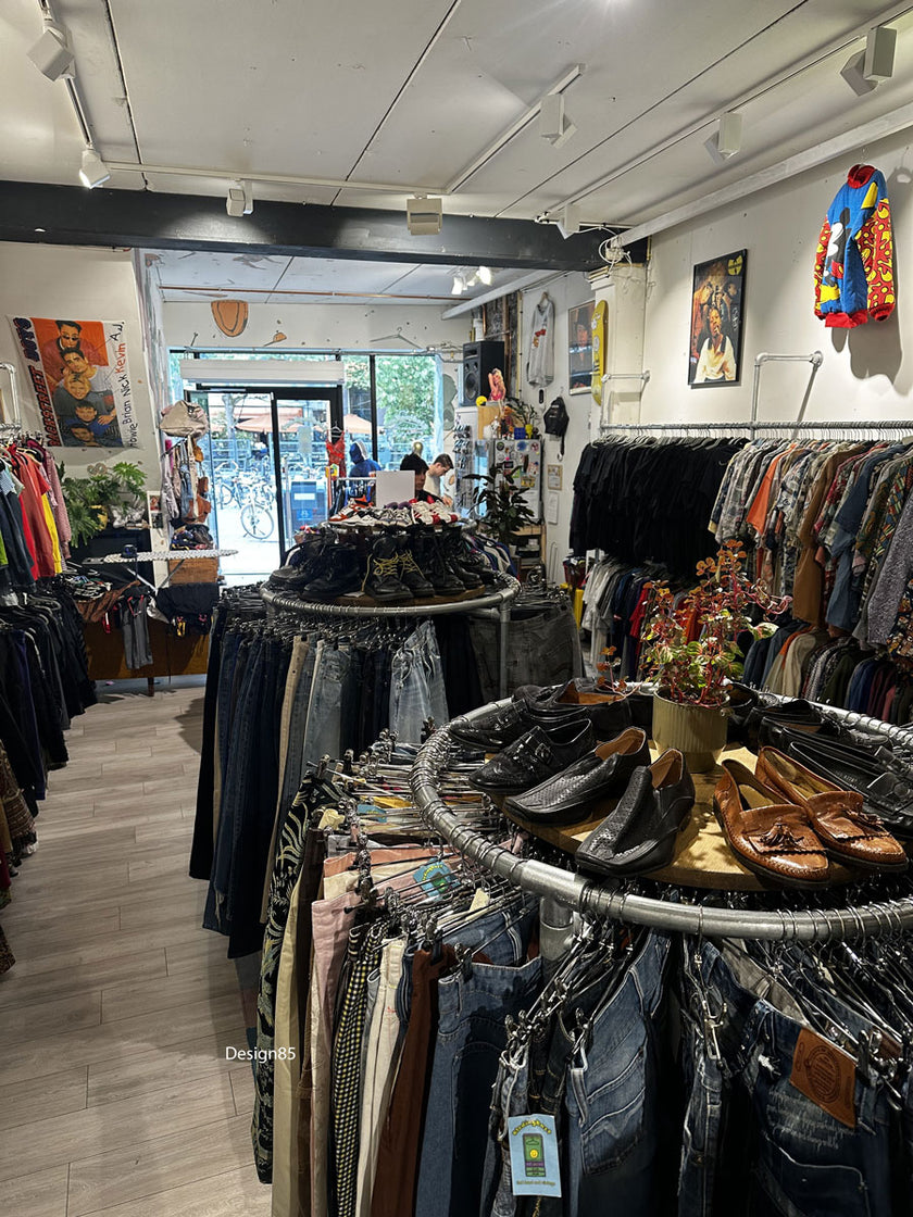 Rond industrieel kledingrek van steigerbuizen met shirts, sneakers en decoratie in een modewinkel.