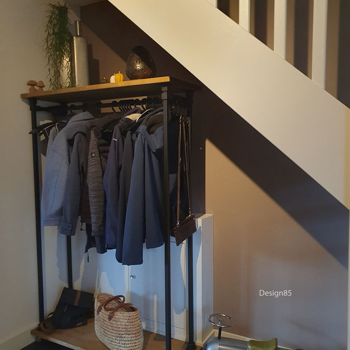 steigerbuis kledingrek vierkant met zwarte kokers en met vurenhout in het bruin. Het kledingrek staat onder een trap.