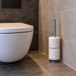 Steigerbuis toiletrolhouder Staand van industrieel staal met twee toiletrollen, stijlvol geplaatst naast een modern toilet.