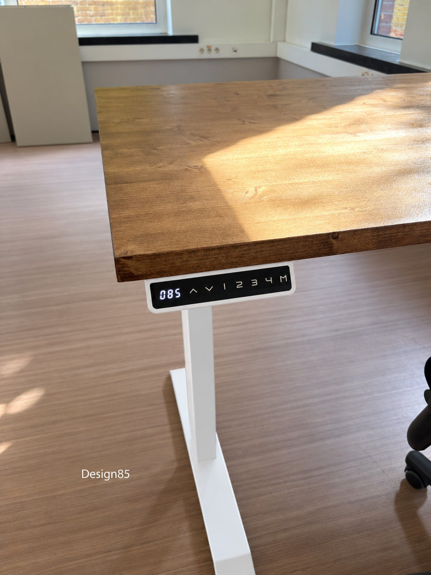 Zit Sta Bureau Elektrisch met stevig vurenhouten werkblad en wit metalen frame, geplaatst in een lichte kantoorruimte met bureaustoel.